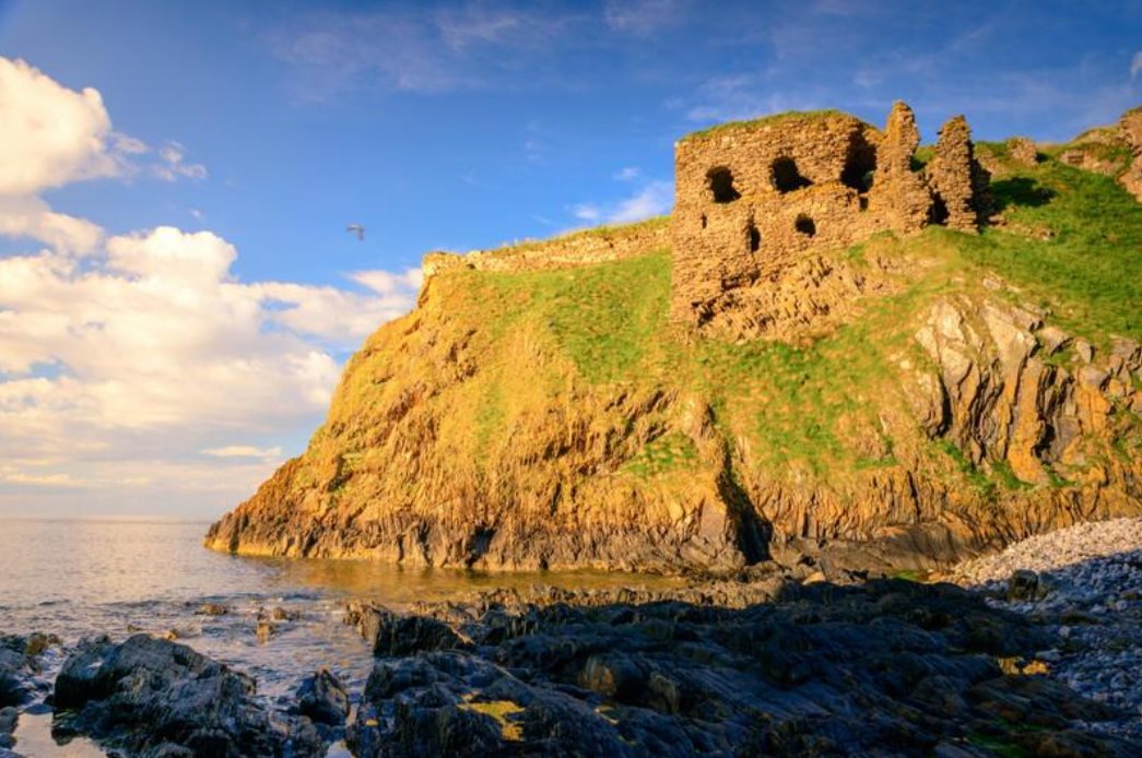 view of findlater castle, cliffs and sea under blue sky